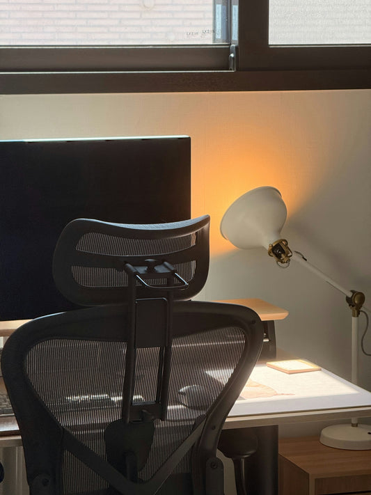 An office space with a chair, lamp, and monitor.